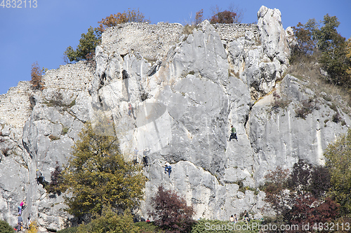 Image of Group of young people climbing natural high rocky wall