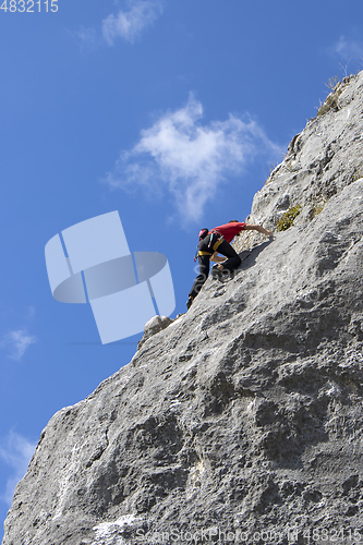Image of Young sports man climbing natural high rocky wall 