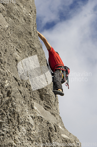 Image of Young sports man climbing natural high rocky wall 