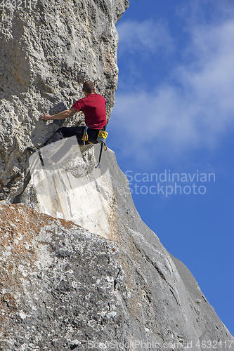 Image of Young sports man climbing natural high rocky wall 