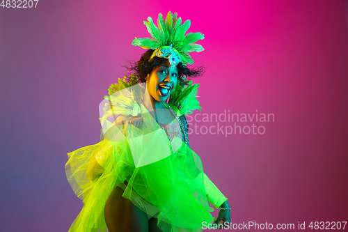 Image of Beautiful young woman in carnival and masquerade costume on gradient studio background in neon light