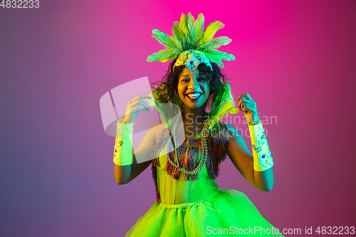 Image of Beautiful young woman in carnival and masquerade costume on gradient studio background in neon light