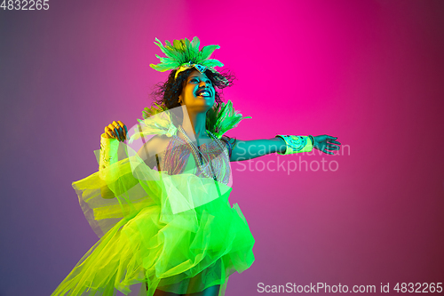 Image of Beautiful young woman in carnival and masquerade costume on gradient studio background in neon light