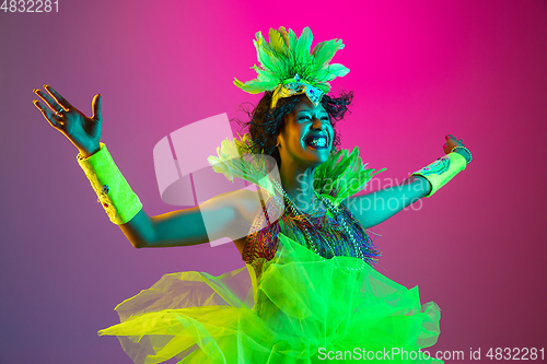 Image of Beautiful young woman in carnival and masquerade costume on gradient studio background in neon light