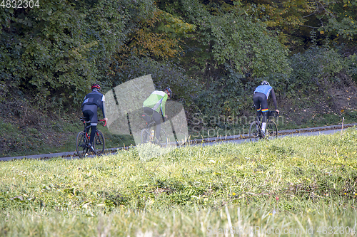 Image of Group athletes cyclists riding a bike uphill along a road