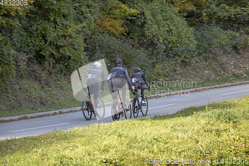 Image of Group athletes cyclists riding a bike uphill along a road