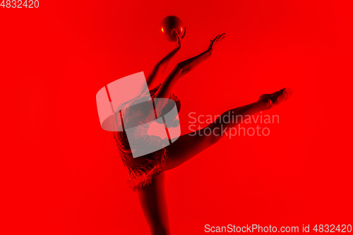 Image of Young flexible female gymnast isolated on red studio background