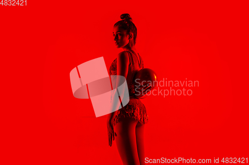 Image of Young flexible female gymnast isolated on red studio background