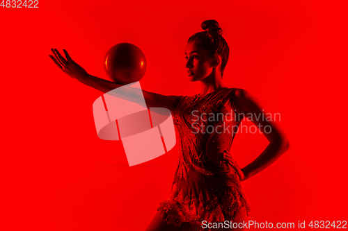 Image of Young flexible female gymnast isolated on red studio background