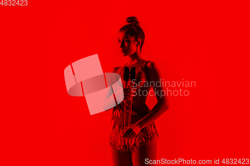 Image of Young flexible female gymnast isolated on red studio background