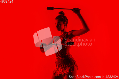 Image of Young flexible female gymnast isolated on red studio background