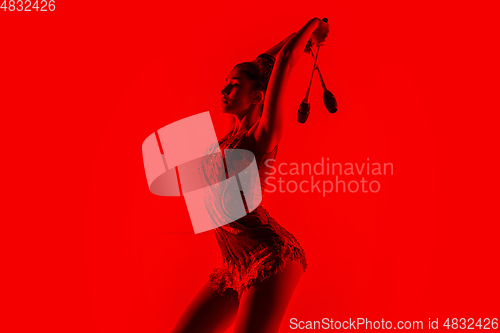 Image of Young flexible female gymnast isolated on red studio background