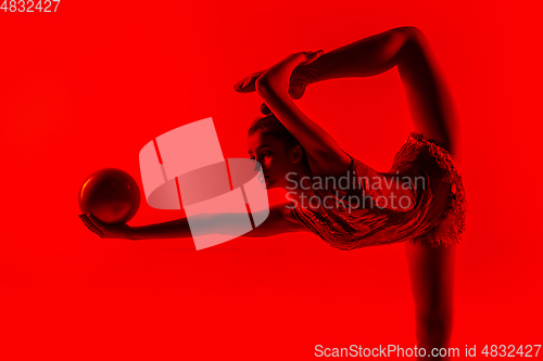 Image of Young flexible female gymnast isolated on red studio background