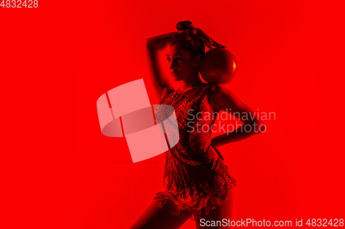 Image of Young flexible female gymnast isolated on red studio background