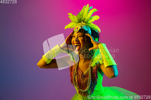 Image of Beautiful young woman in carnival and masquerade costume on gradient studio background in neon light