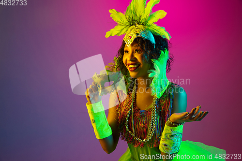 Image of Beautiful young woman in carnival and masquerade costume on gradient studio background in neon light