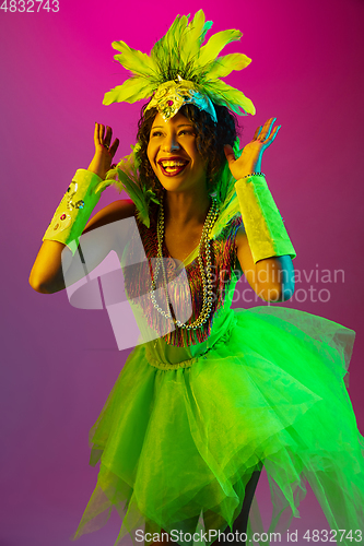 Image of Beautiful young woman in carnival and masquerade costume on gradient studio background in neon light