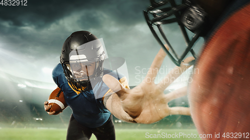 Image of American football players in fight for goal at stadium in flashlights. Professional sportsman during game playing in action and motion.