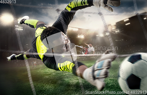 Image of African male soccer or football player, goalkeeper in action at stadium. Young man catching ball, training, protecting goals in motion.