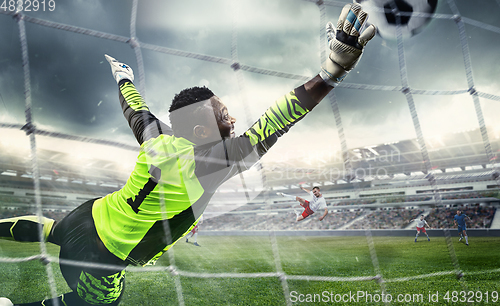 Image of African male soccer or football player, goalkeeper in action at stadium. Young man catching ball, training, protecting goals in motion.