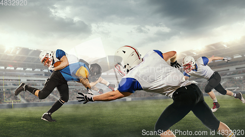 Image of American football players in fight for goal at stadium in flashlights. Professional sportsman during game playing in action and motion.