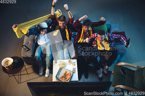 Image of Group of friends watching TV, sport match together. Emotional fans cheering for favourite team. Top view. Concept of friendship, leisure activity, emotions