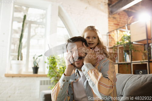 Image of Happy father and little cute daughter at home. Family time, togehterness, parenting and happy childhood concept. Weekend with sincere emotions.