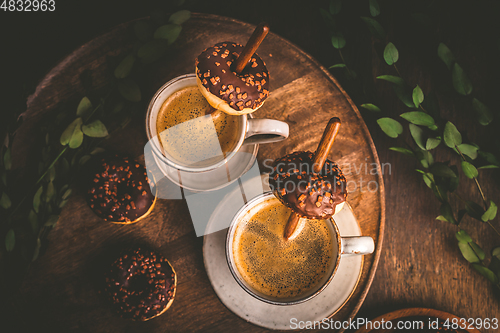 Image of Two cups of Caffe Americano with small chocolate donuts