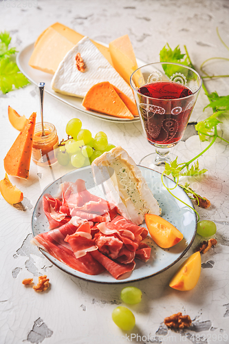 Image of Ham and cheese platter with grapes and red wine