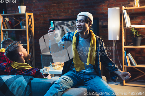 Image of Group of friends watching TV, sport match together. Emotional fans cheering for favourite team, watching on exciting game. Concept of friendship, leisure activity, emotions