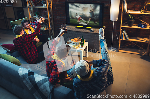 Image of Group of friends watching TV, sport match together. Emotional fans cheering for favourite team, watching on exciting game. Concept of friendship, leisure activity, emotions