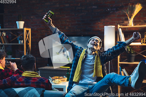 Image of Group of friends watching TV, sport match together. Emotional fans cheering for favourite team, watching on exciting game. Concept of friendship, leisure activity, emotions