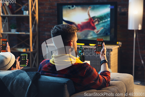 Image of Group of friends watching TV, sport match together. Emotional fans cheering for favourite team, watching on exciting game. Concept of friendship, leisure activity, emotions