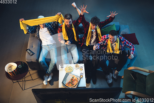 Image of Group of friends watching TV, sport match together. Emotional fans cheering for favourite team. Top view. Concept of friendship, leisure activity, emotions