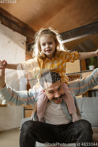 Image of Happy father and little cute daughter at home. Family time, togehterness, parenting and happy childhood concept. Weekend with sincere emotions.