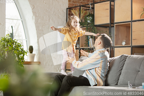 Image of Happy father and little cute daughter at home. Family time, togehterness, parenting and happy childhood concept. Weekend with sincere emotions.