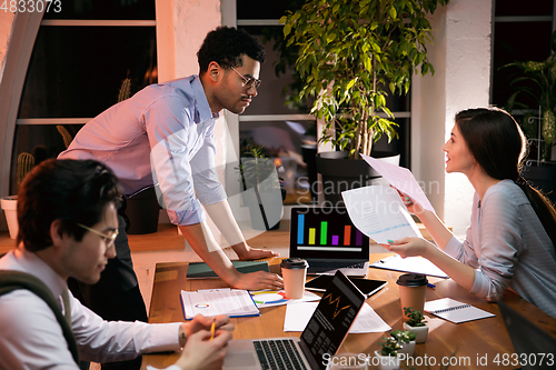 Image of Colleagues working together in modern office using devices and gadgets during creative meeting