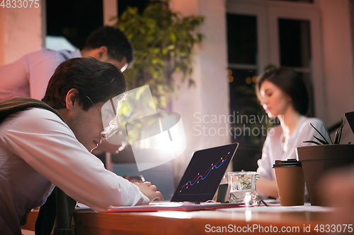 Image of Colleagues working together in modern office using devices and gadgets during creative meeting