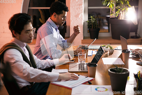 Image of Colleagues working together in modern office using devices and gadgets during creative meeting