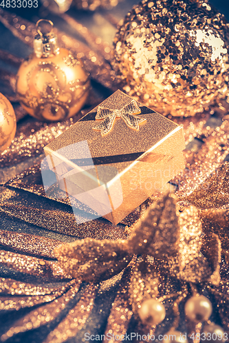 Image of Christmas ornaments with small present in golden tones