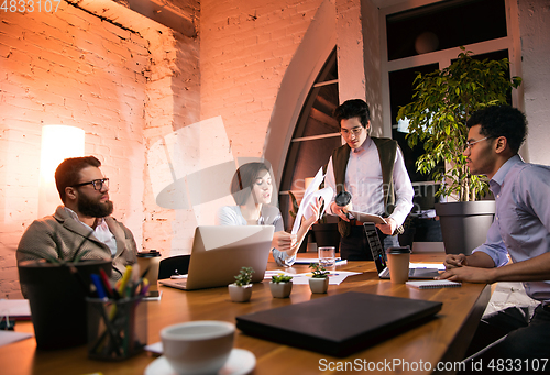 Image of Colleagues working together in modern office using devices and gadgets during creative meeting