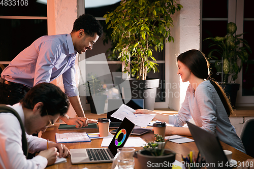 Image of Colleagues working together in modern office using devices and gadgets during creative meeting