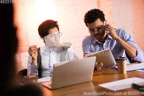 Image of Colleagues working together in modern office using devices and gadgets during creative meeting