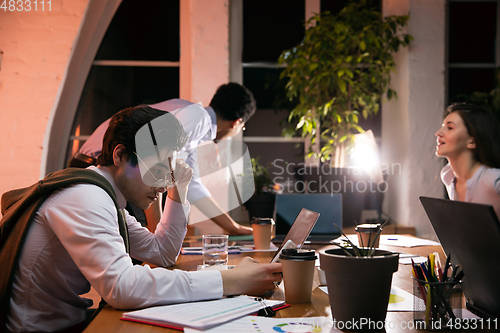 Image of Colleagues working together in modern office using devices and gadgets during creative meeting