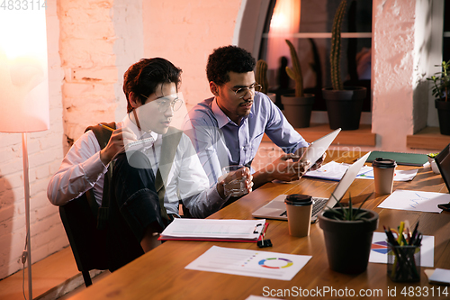 Image of Colleagues working together in modern office using devices and gadgets during creative meeting