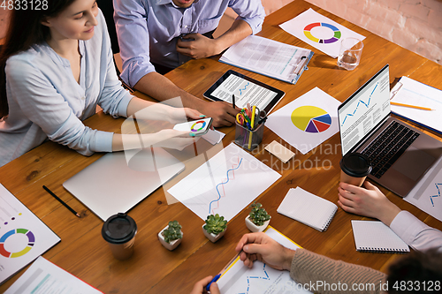 Image of Colleagues working together in modern office using devices and gadgets during creative meeting