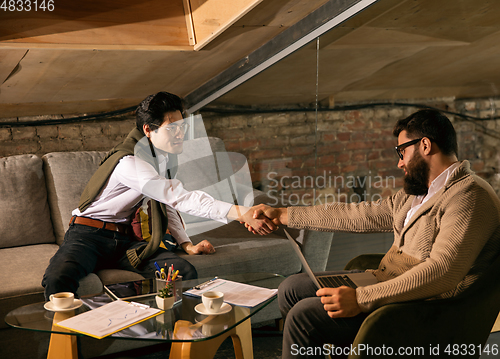 Image of Colleagues working together in modern office using devices and gadgets during creative meeting