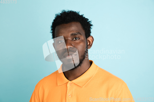 Image of African man\'s portrait isolated over blue studio background with copyspace