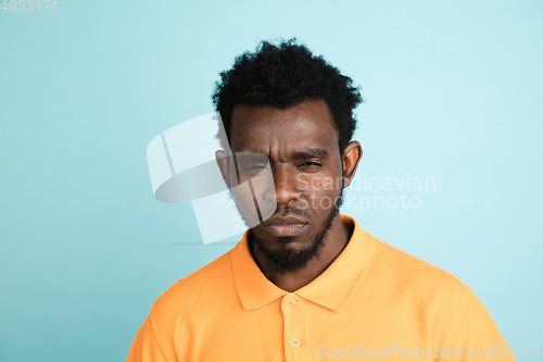 Image of African man\'s portrait isolated over blue studio background with copyspace