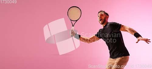 Image of Young caucasian man playing tennis isolated on pink studio background, action and motion concept